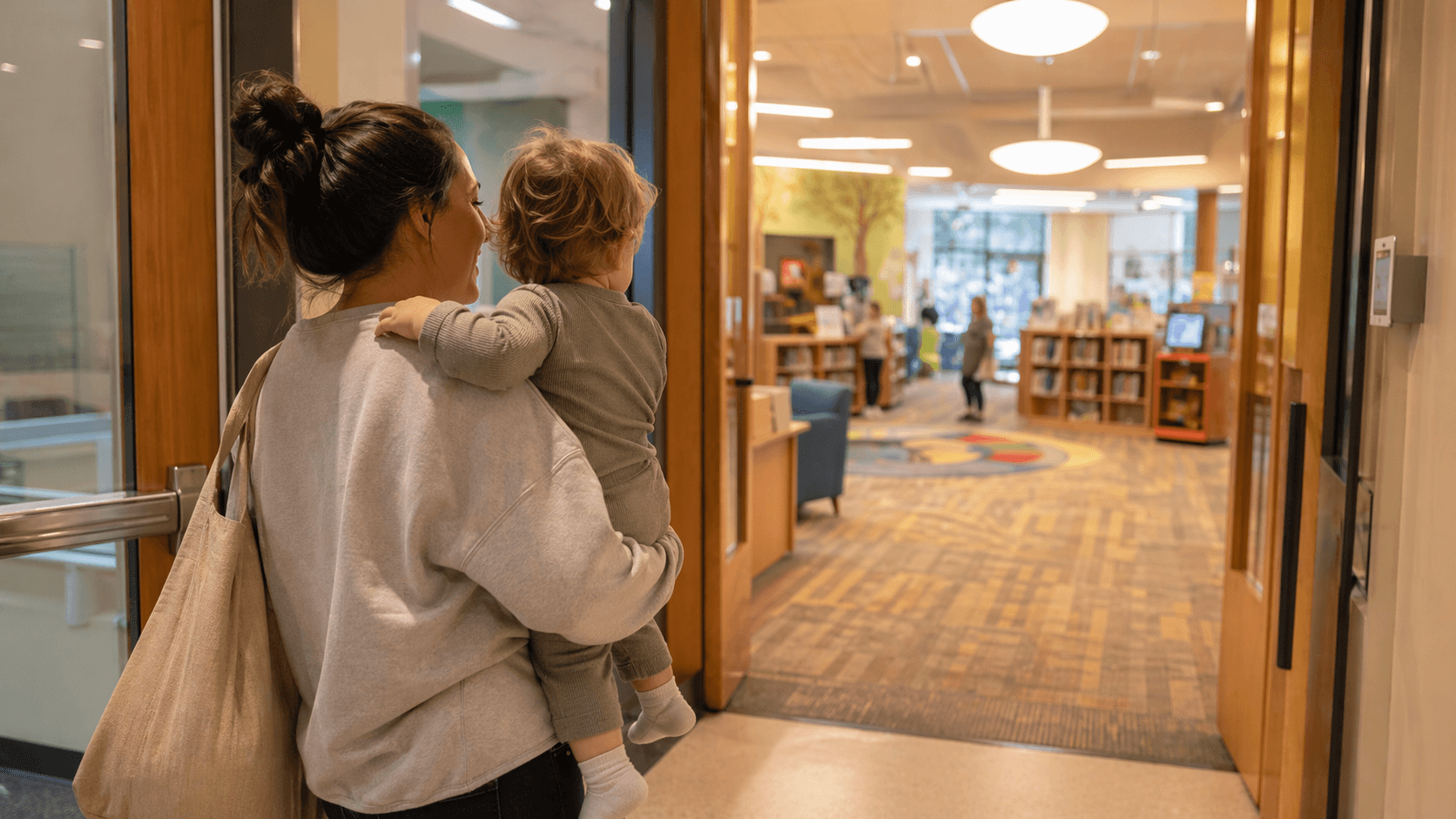 Parent carrying a toddler into a free indoor activity space
