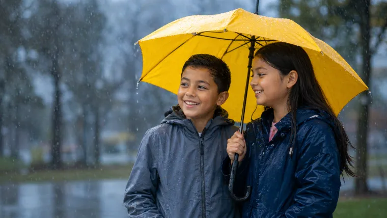 Children under a yellow umbrella on a rainy day